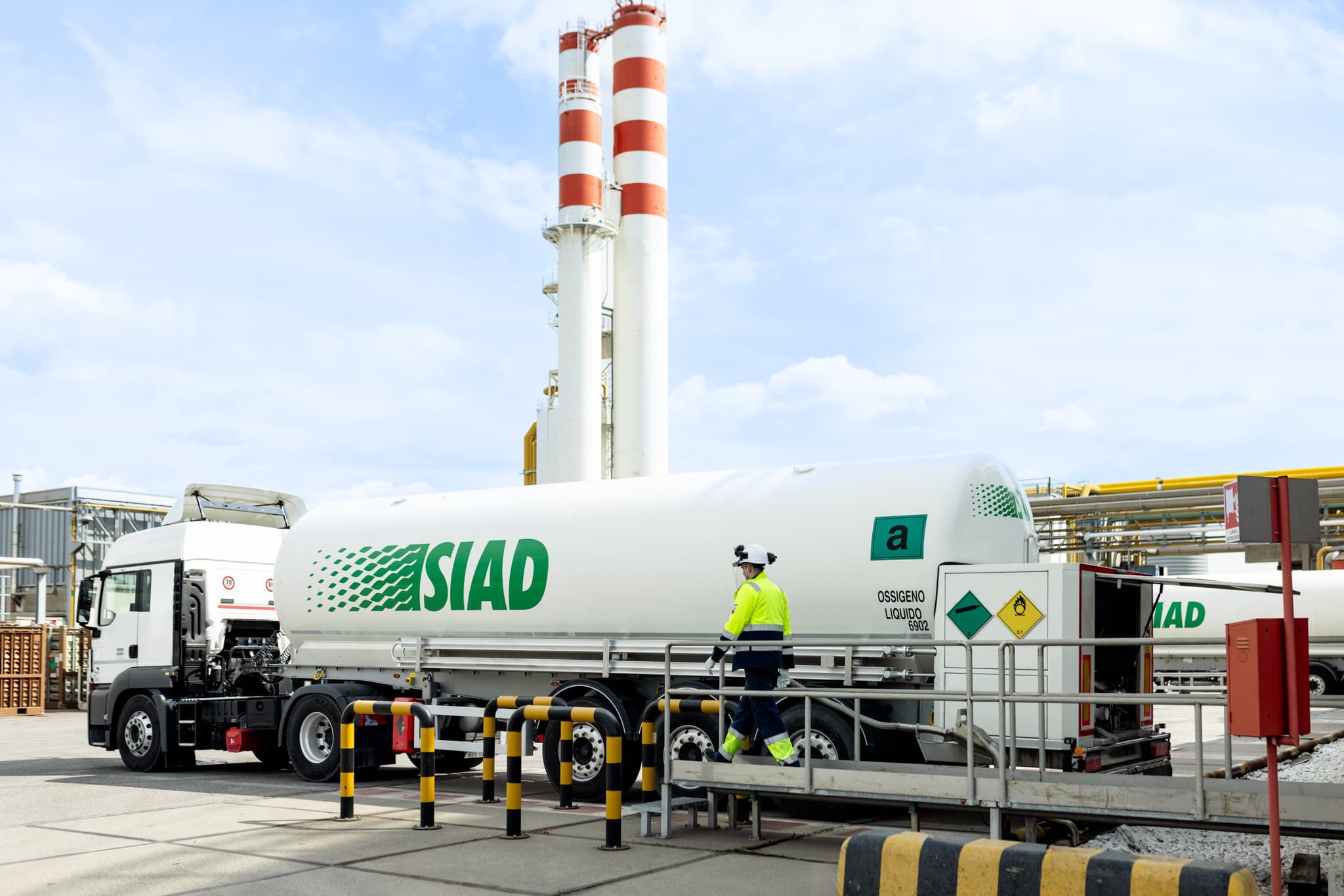 SIAD tanker truck delivering liquid oxygen at industrial plant with safety worker
